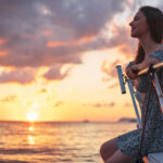 Young attractive woman sitting on the deck of the yacht and enjoying sunset