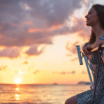 Young attractive woman sitting on the deck of the yacht and enjoying sunset